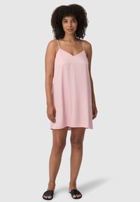 Abito senza maniche di un rosa chiaro con scollatura a V e spalline sottili. Realizzato in tessuto morbido, che arriva poco sopra il ginocchio, abbinato a sandali neri con la suola a scivolo.