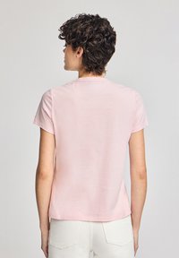 Kortärmad rosa bomullsskjorta med rundad halsringning; slät textur, rak skärning och subtil glans. Bakifrån visas axelsömmar och ärmar.