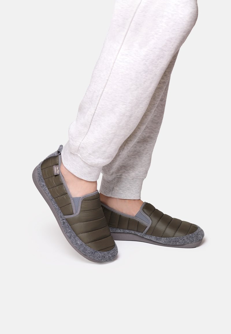 Gröna slip-on-skor med en kviltad ovandel, grå detaljer och en grå filtliknande sula, tillsammans med ljusgrå sweatpants.