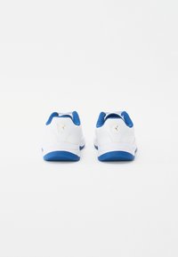Valkoiset Puma-tennarit sinisillä pohjilla ja vuorauksella, näkyen takakuvasta valkoista taustaa vasten.