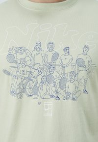 Hele roheline puuvillane t-särk, millel on sinine joonistatud illustratsioon erinevate isikute, sealhulgas kohandatud sportlase, kes hoiavad tennisereketit.