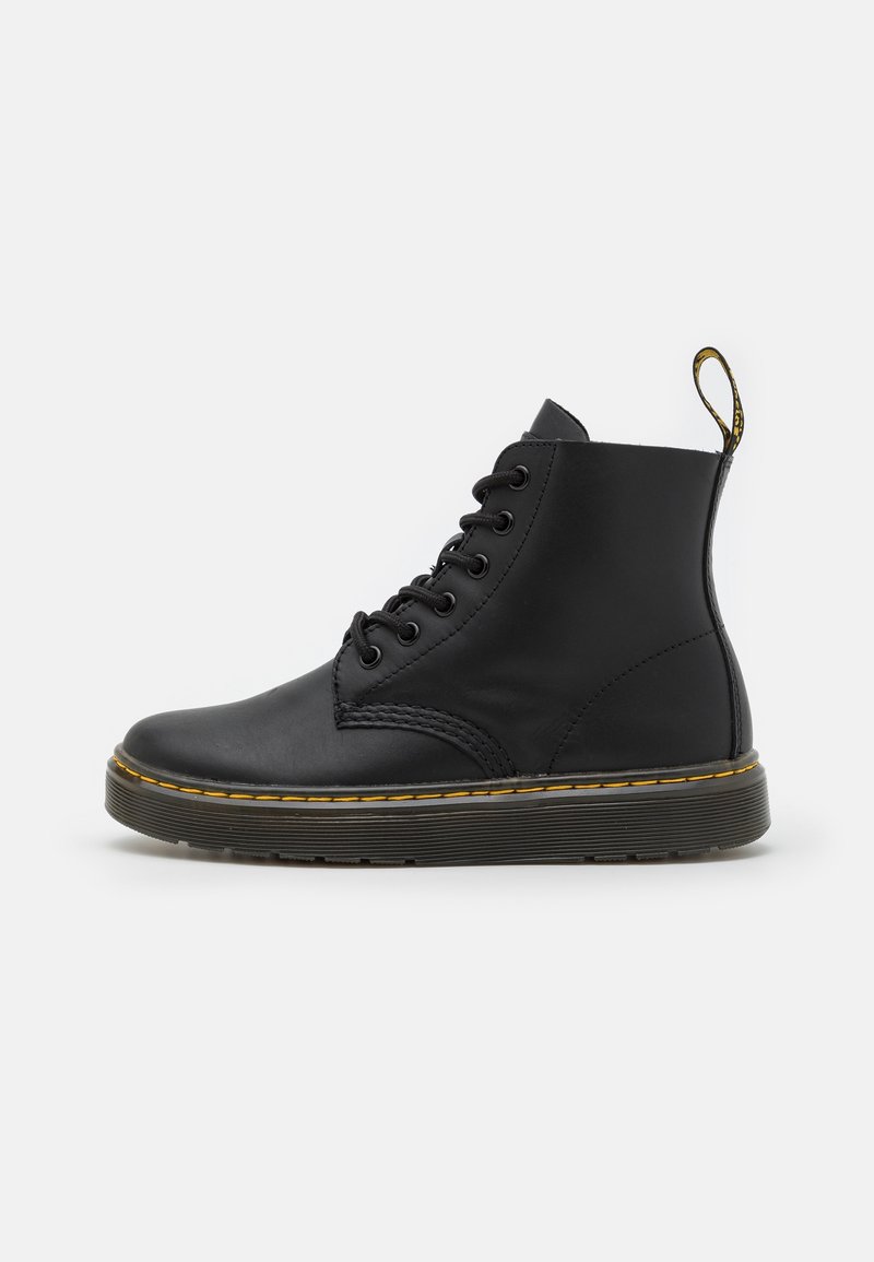 Bottine en cuir noir à lacets avec surpiqûres jaunes et languette à l'arrière, présentée sur fond blanc.