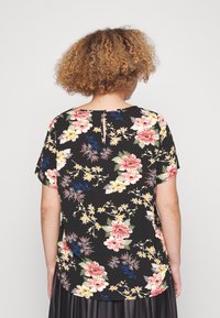Floral short-sleeve top in black with a vibrant multicolored flower pattern. Back features a keyhole opening at the neck.