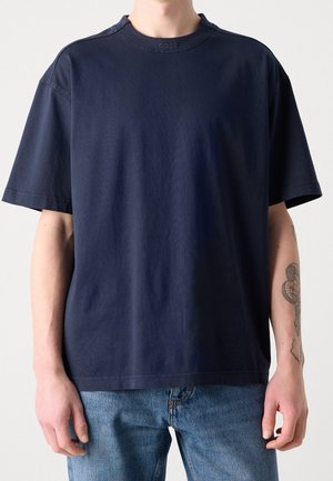 Navyblaue T-Shirt mit kurzen Ärmeln und Rundhalsausschnitt aus strukturiertem Stoff. Mit dezenten Logodetails am Kragen.