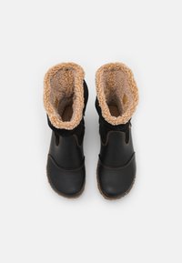 Zwarte laarzen met een lederen buitenkant met textuur en een pluizige, bruine voering. Voorzien van bruine stiksels en een lage, geribbelde zool.