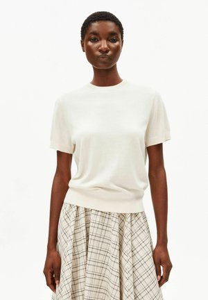 Hellcremiges Strickoberteil mit kurzen Ärmeln, weiche Textur, rundem Ausschnitt, kombiniert mit einem karierten Rock in Beige- und Schwarztönen.