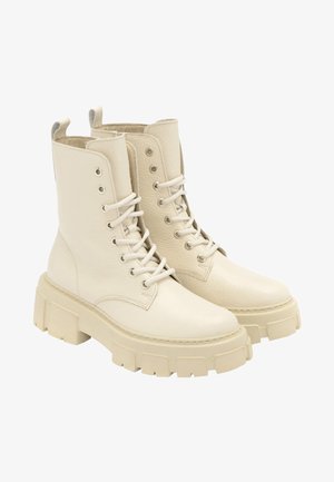 Białe skórzane buty wojskowe z grubą platformą, sznurowane z przodu i okrągłym noskiem. Posiadają gładkie wykończenie oraz wzmocnione oczka.