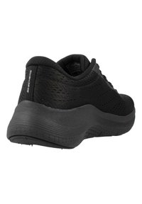 Czarny but sportowy z lekką, perforowaną siateczką u góry, podkreślony grubą gumową podeszwą i subtelnym logo na pięcie.