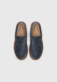 Marineblaue Schnürschuhe aus weichem Wildleder, mit kontrastierenden braunen Gummisohlen und minimalen Nähakzenten.