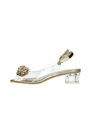 Sandale transparente à talon bas avec décoration florale dorée sur la bride avant, talon bloc transparent, et bride ajustable à la cheville avec boucle dorée.