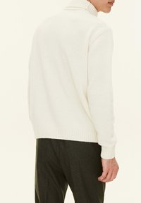 Weißer Strickpullover mit hohem Kragen, gerippten Bündchen und Saum sowie legerem Schnitt. Die Textur wirkt weich und gemütlich, ideal für kältere Witterung.
