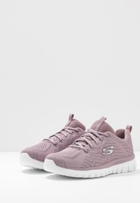 Licht paarse sportchoenen met een ademende mesh bovenkant, vetersluiting en een witte rubberen zool met gestructureerde profielpatronen.