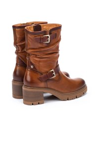 Botas de cuero marrón hasta el tobillo con un diseño arrugado, que cuentan con dos hebillas decorativas, un tacón grueso y una suela texturizada.