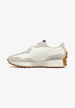 Vue latérale d'une chaussure de sport New Balance beige et blanche avec semelle en gomme et design à lacets sur fond blanc.