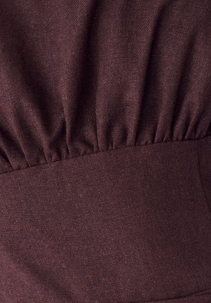 Hnedá textúrovaná látka s naťahovaním v oblasti pásu. Hladký povrch so súvislým vzorom tkania.