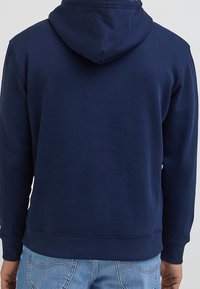 Felpa blu navy con finitura testurizzata, tasca a marsupio e cappuccio con cordino, dotata di polsini e orlo a coste per un look aderente.