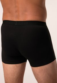 Boxers noirs en coton doux, dotés d'une ceinture lisse avec un logo embossé ; coupe ajustée mettant en valeur la silhouette du corps.