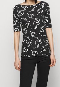 Svart kortärmad topp med ett vitt mönster av ankare och kedjor, med en båtformad halsringning och en smal passform genom hela kroppen.