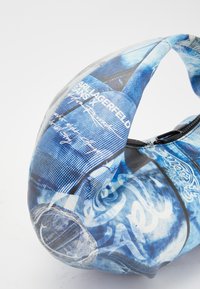 Blue patterned handbag made of glossy material, featuring abstract prints and handwriting, with a rounded shape and black zipper closure.