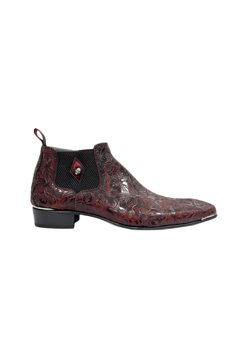 Botas de cuero rojo hasta el tobillo con intrincados relieves florales, paneles laterales elásticos negros y punta redondeada, con un pequeño detalle decorativo de calavera.