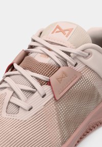 Lichtroze sportshoe met mesh stof, textuuraccenten en gladde overlays. Bevat een prominent logo en tonale veters.