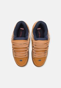 Orange leather sneakers with navy textile lining, flat laces, padded collar, and a blue logo on the side. Textured detail on the upper.