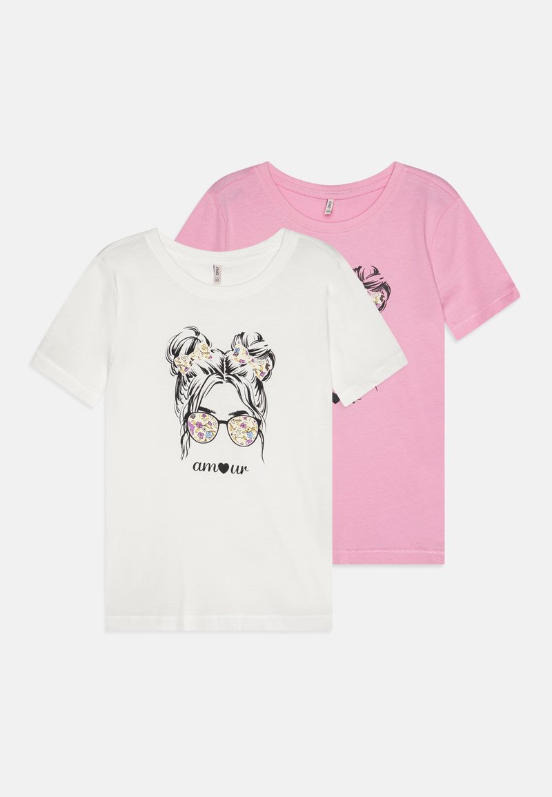 Dos camisetas: una blanca y una rosa. Ambas presentan un gráfico de una chica con gafas y la palabra "amour" abajo, hechas de algodón suave.