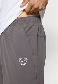 Γκρίζες Nike σορτσάκια με ελαστική ζώνη, πλαϊνές τσέπες και λε υκή πινακίδα λογότυπου. Το ύφασμα είναι λείο με ελαφριά γυαλάδα.