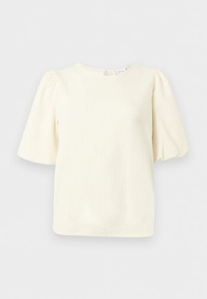 Blusa color crema con texture, maniche corte a sbuffo e scollo rotondo, mostrata su uno sfondo semplice.