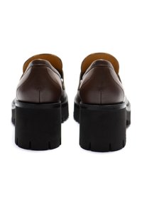 Scarpe in pelle marrone con un design arrotondato, tallone rialzato e suole in gomma nera spessa con bordo testurizzato.