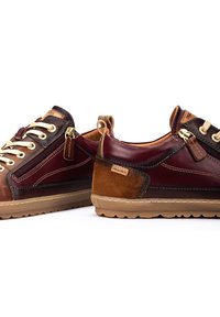 Zapatillas de cuero marrón y burdeos con cordones beige, una cremallera lateral y suelas de goma marrón claro; presentan una mezcla de texturas y una etiqueta con el logo.