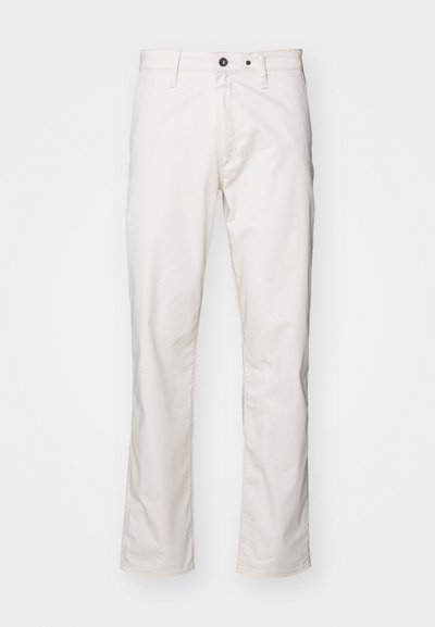 Balti medvilniniai kelnių su tiesiomis kojomis, turintys dvi priekinės kišenes ir dvi galinės kišenes, mygtuko uždarymą ir minimalų siuvimo detalių kiekį.