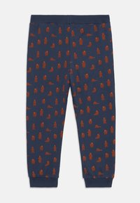 Marineblauwe katoenen legging met een herhaald patroon van rode beren, zachte textuur, elastische tailleband en aansluitende enkels.