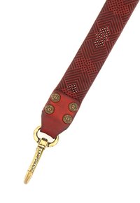 Cinturino in pelle rossa con motivi geometrici, accessoriato con metallo dorato e rivetti decorativi. Texture liscia con perforazioni nel design.