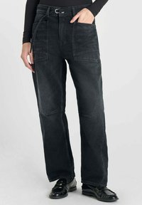 Pantalons en denim noir à coupe ample, dotés de grandes poches avant, d'une taille ceinturée et de jambes droites. Texture lisse avec un léger effet usé.