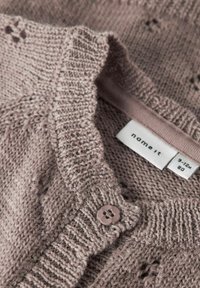 Cardigan lavorato a maglia di un leggero color malva con scollo rotondo, motivi testurizzati e chiusura con un singolo bottone. L'etichetta indica la taglia 9-12 mesi.