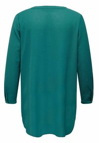 Haut à manches longues couleur sarcelle avec un col arrondi, un tissu doux et texturé, un ourlet arrière plus long et un détail de bouton aux poignets.