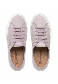 Lila sneakers med en texturerad tygöverdel, vit gummisul, och snörningsdesign. Korkinsåle med synlig logotyp.