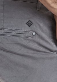 Grau Baumwollhosen mit einer Klappentasche, die mit einem Diamant-Logo-Patch, einer Obersteppnaht und einem silbernen Knopfverschluss versehen ist.