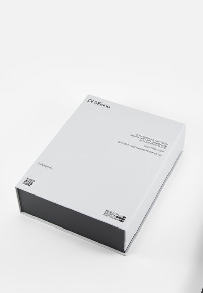 Hvid rektangulær kasse med mat overflade, prydet med sorte accenter, QR-kode og tekst, der beskriver produktets design og forskning.