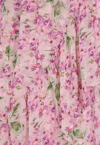 Tessuto floreale con uno sfondo rosa pallido, caratterizzato da grappoli di fiori viola e rossi e fogliame verde, texture leggera e trasparente.
