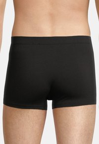 Black boxer briefs made of smooth fabric, featuring a simple design, elastic waistband, and mid-thigh length. No patterns or accents visible.