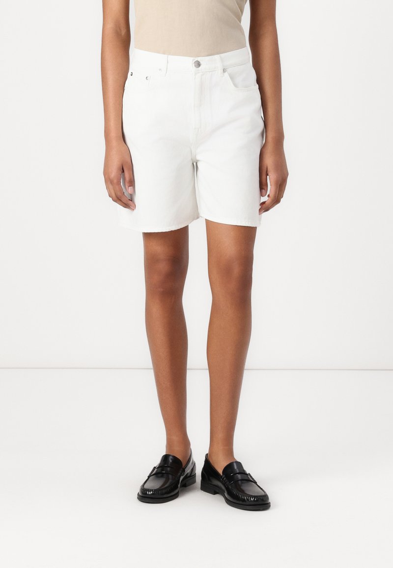 Shorts de mezclilla blanca con corte recto, que cuentan con cierre de botón, cinco bolsillos y un dobladillo limpio. Textura suave y tela ligera.