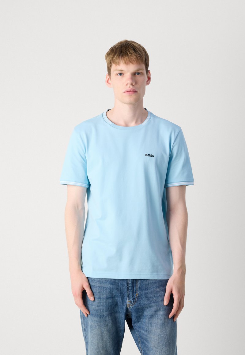 T-shirt en coton bleu clair à manches courtes, col rond et accents de rayures subtils. Présente un petit logo noir "BOSS" sur la poitrine.