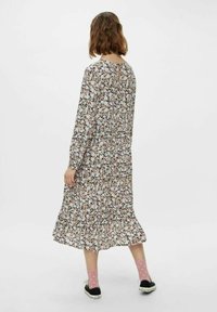 Blommig midiklänning med lång ärm, med en svart bakgrund och pastellfärgade blommor. Detalj med nyckelhål i ryggen och utsvängd nederkant.