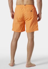 Pánské plavky v jasně oranžové barvě, s volným střih a elastickým pasem, a dvěma zadními kapsami s jemným logem značky.