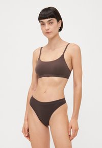 Smeđi bikini set od rastezljivog materijala s elegantnim bralet topom i gaćicama visokog struka. Tanke naramenice, glatka tekstura i suptilan dizajn.
