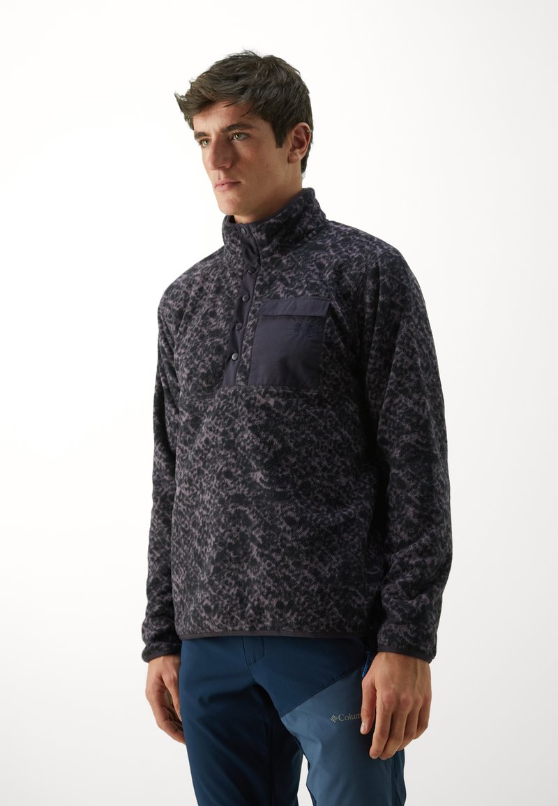Polarowy sweter w ciemnoszarym kolorze z subtelnym wzorem, z wysokim kołnierzem, zapięciem na guziki oraz kieszenią na piersi z akcentem z ciemnego materiału.