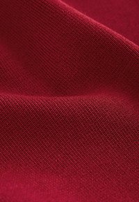 Tissu bordeaux avec une texture lisse, présentant de fins motifs en relief et une apparence tissée homogène.