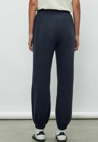 Mörkblå sweatpants med elastisk midja och ribbade muddar. Mjuk, slät tyg med avslappnad passform, stilren med diskreta sidsömmar.